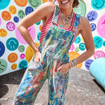 Cotton denim overalls with adjustable straps and sides with metal buttons in a paint splatter detail in cobalt blue, orange, green and yellow washed color with knee darts.