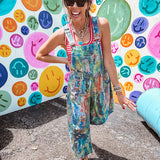 Cotton denim overalls with adjustable straps and sides with metal buttons in a paint splatter detail in cobalt blue, orange, green and yellow washed color with knee darts.