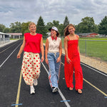 Soft, stretchy cream elastic drawstring waist pants with large red polka dots throughout, pockets and button cuffs for a balloon-like silhouette.