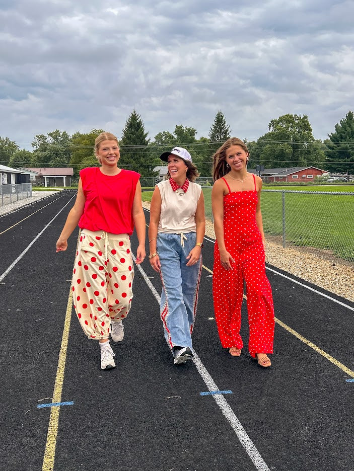 Soft, stretchy cream elastic drawstring waist pants with large red polka dots throughout, pockets and button cuffs for a balloon-like silhouette.