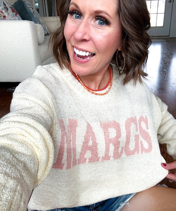Nearly sheer soft, woven cream sweater with coral "MARGS" on the front.