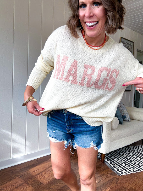 Nearly sheer soft, woven cream sweater with coral "MARGS" on the front.