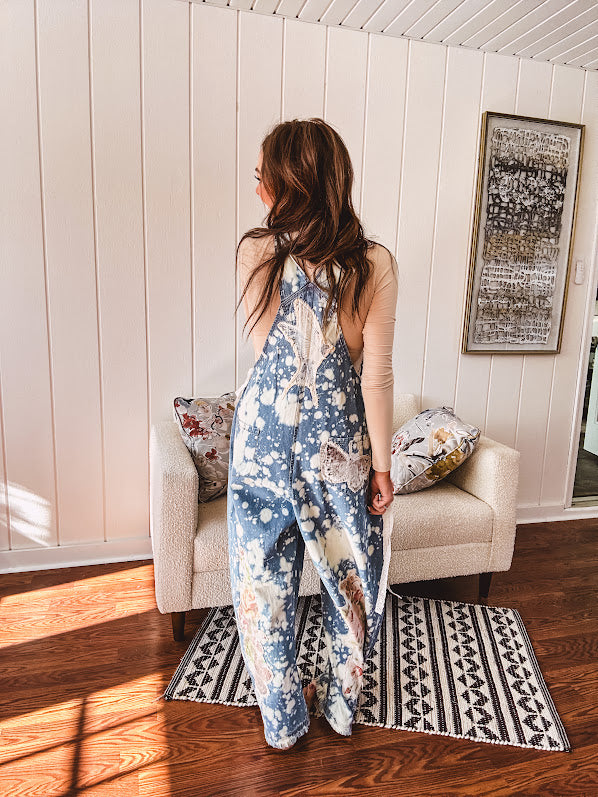 Denim patchwork overalls with tied adjustable straps, lace tied sides and floral and butterfly patches throughout.