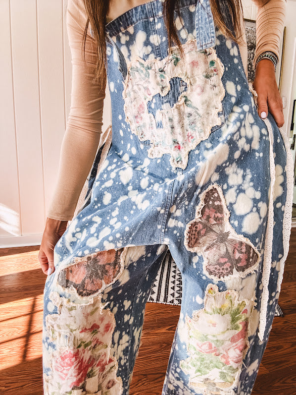 Denim patchwork overalls with tied adjustable straps, lace tied sides and floral and butterfly patches throughout.