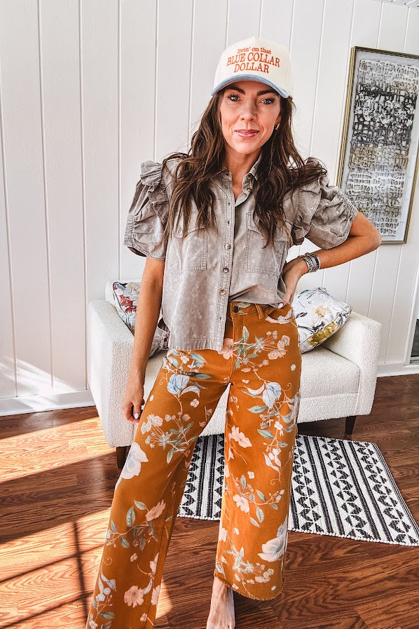 Dark mustard denim stretch pants with vintage floral print, button zipper closure, wide leg and raw hem.