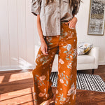 Dark mustard denim stretch pants with vintage floral print, button zipper closure, wide leg and raw hem.