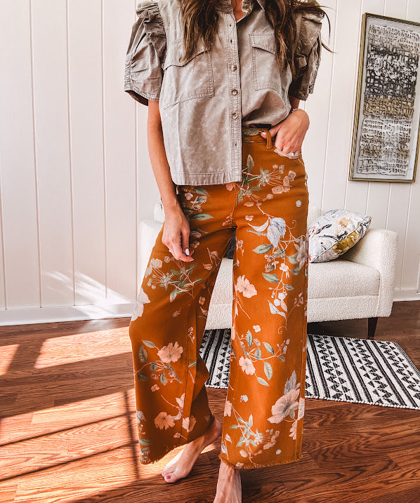 Dark mustard denim stretch pants with vintage floral print, button zipper closure, wide leg and raw hem.
