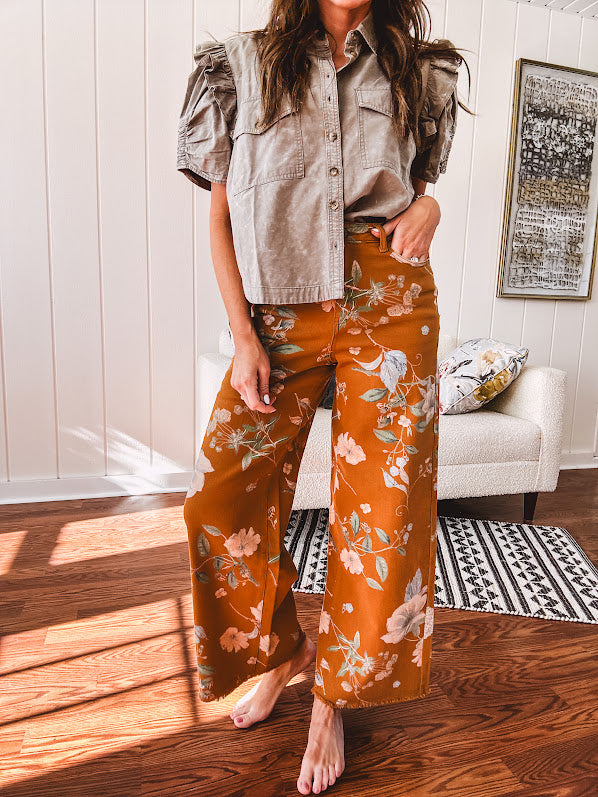 Dark mustard denim stretch pants with vintage floral print, button zipper closure, wide leg and raw hem.