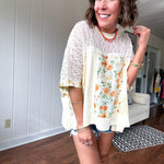 Cream lace crochet dolman style tee with orange and green floral patch and trim. Oversized.
