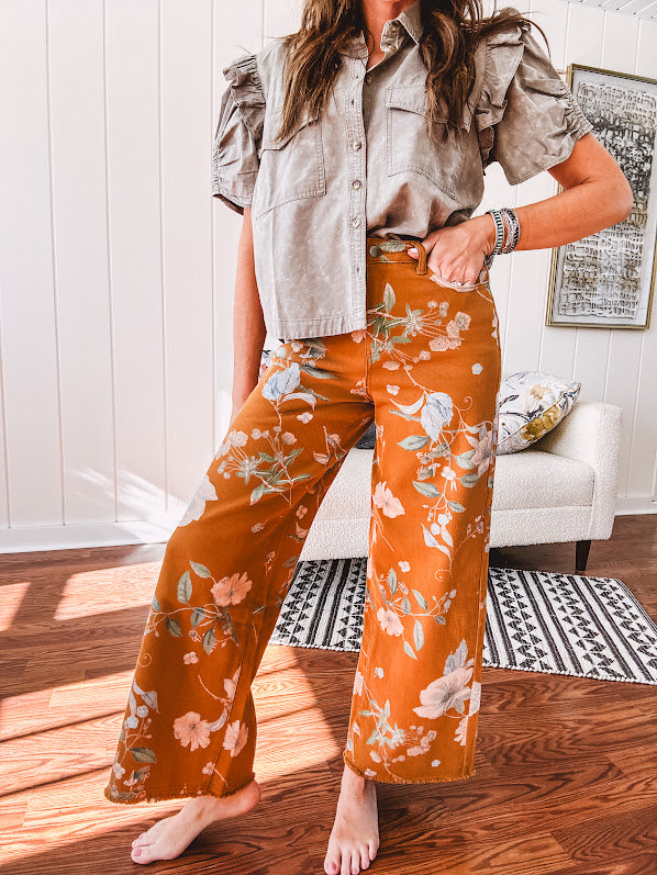 Dark mustard denim stretch pants with vintage floral print, button zipper closure, wide leg and raw hem.