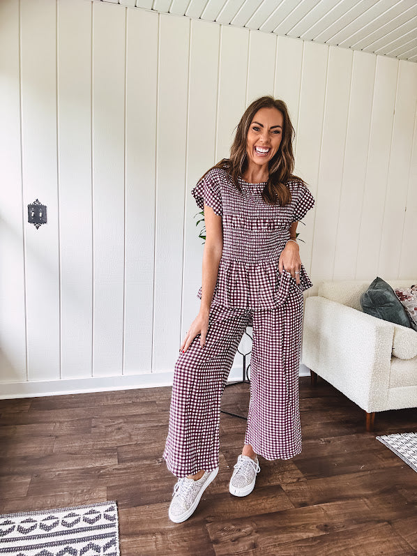 Plum and white gingham set with round neck top with smocking detail throughout and scalloped short sleeves and elastic waist wide leg pants with scalloped hem.