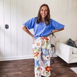 Wide leg cream pants with elastic drawstring waist, pockets and a bright red, blue and green tropical floral print and shorts lining.