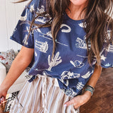 Navy short sleeved cotton top with ivory western motif print, waist length, cuffed sleeves.