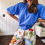 Wide leg cream pants with elastic drawstring waist, pockets and a bright red, blue and green tropical floral print and shorts lining.
