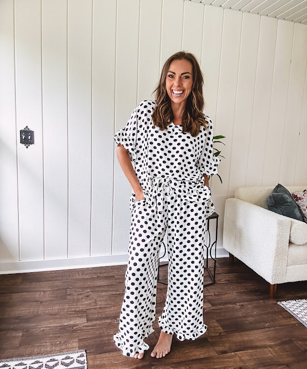Lightweight white or black short sleeved top with black or white polka dots throughout with V neck, short ruffled sleeves and ruffled hem.