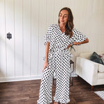 Lightweight white or black short sleeved top with black or white polka dots throughout with V neck, short ruffled sleeves and ruffled hem.