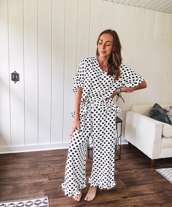 Lightweight white or black short sleeved top with black or white polka dots throughout with V neck, short ruffled sleeves and ruffled hem.
