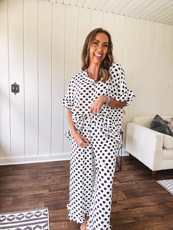 Lightweight white or black short sleeved top with black or white polka dots throughout with V neck, short ruffled sleeves and ruffled hem.