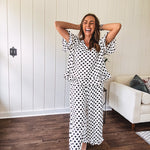 Lightweight white or black short sleeved top with black or white polka dots throughout with V neck, short ruffled sleeves and ruffled hem.