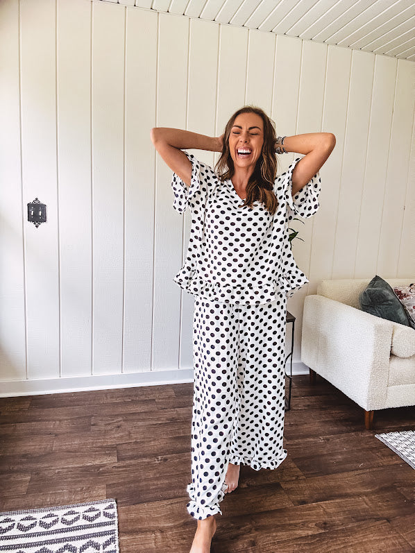 Lightweight white or black short sleeved top with black or white polka dots throughout with V neck, short ruffled sleeves and ruffled hem.