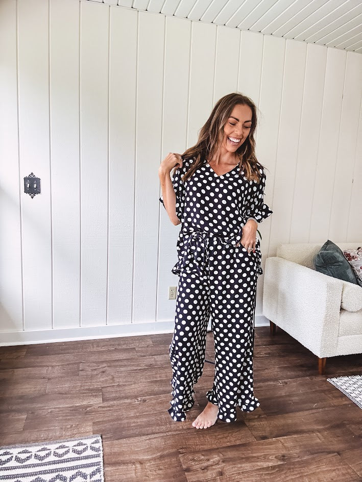 Lightweight white or black short sleeved top with black or white polka dots throughout with V neck, short ruffled sleeves and ruffled hem.