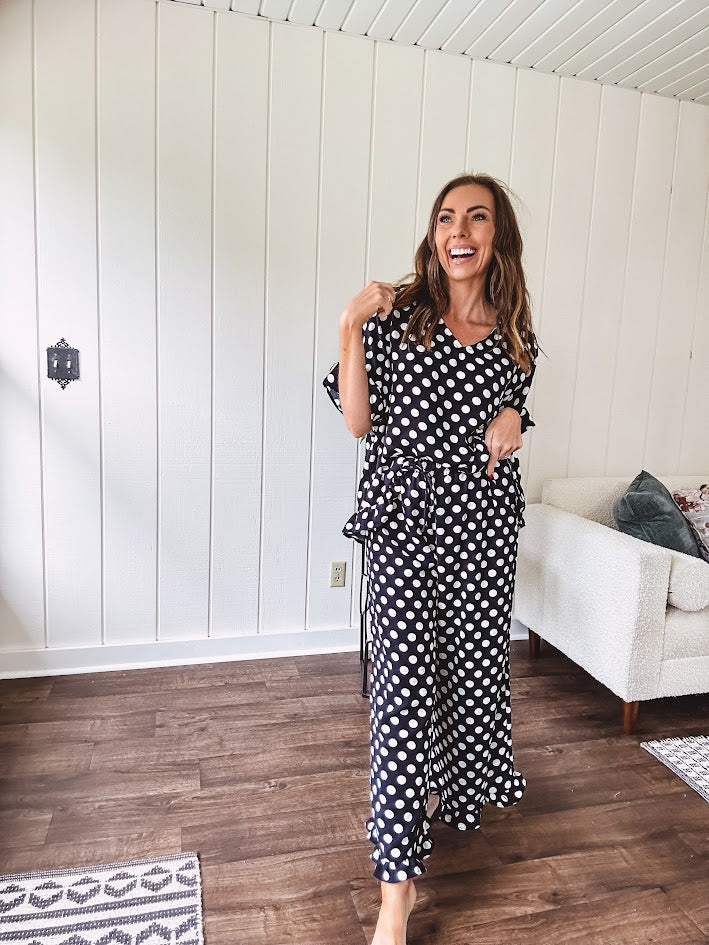 Lightweight white or black short sleeved top with black or white polka dots throughout with V neck, short ruffled sleeves and ruffled hem.