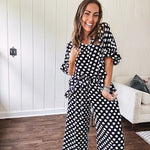 Lightweight white or black short sleeved top with black or white polka dots throughout with V neck, short ruffled sleeves and ruffled hem.