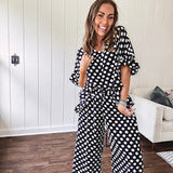 Lightweight white or black short sleeved top with black or white polka dots throughout with V neck, short ruffled sleeves and ruffled hem.