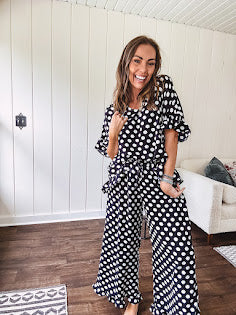 Lightweight white or black short sleeved top with black or white polka dots throughout with V neck, short ruffled sleeves and ruffled hem.