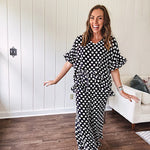 Lightweight white or black short sleeved top with black or white polka dots throughout with V neck, short ruffled sleeves and ruffled hem.