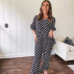 Lightweight white or black short sleeved top with black or white polka dots throughout with V neck, short ruffled sleeves and ruffled hem.