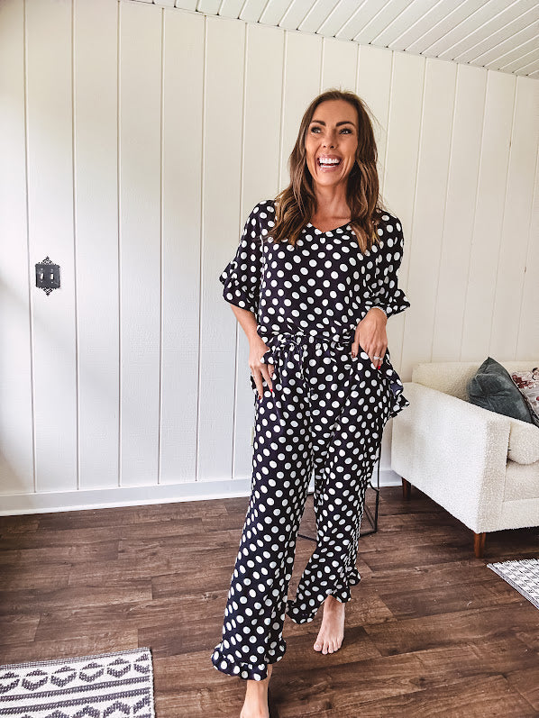 Lightweight white or black short sleeved top with black or white polka dots throughout with V neck, short ruffled sleeves and ruffled hem.