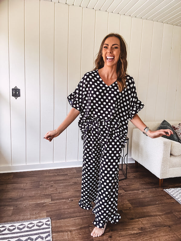 Lightweight white or black short sleeved top with black or white polka dots throughout with V neck, short ruffled sleeves and ruffled hem.