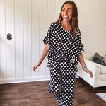 Lightweight white or black short sleeved top with black or white polka dots throughout with V neck, short ruffled sleeves and ruffled hem.