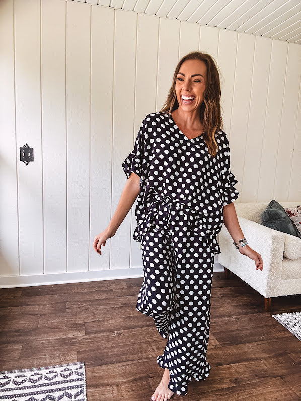 Lightweight white or black short sleeved top with black or white polka dots throughout with V neck, short ruffled sleeves and ruffled hem.