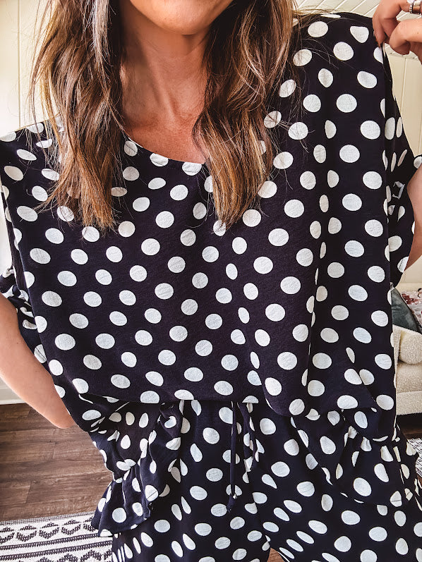 Lightweight white or black short sleeved top with black or white polka dots throughout with V neck, short ruffled sleeves and ruffled hem.