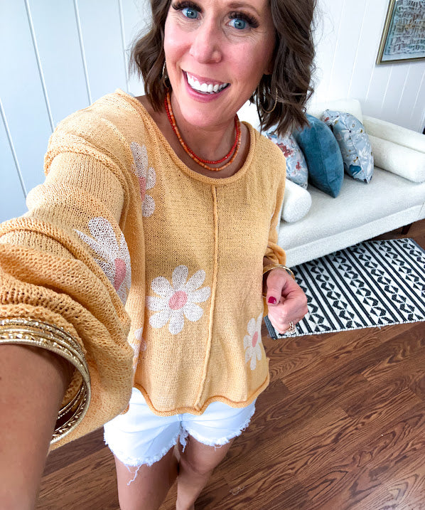 Soft, lightweight, nearly sheer knit pullover  with long sleeves, exposed seams at the shoulders and down the center with large daisy florals throughout. Available in multiple colors.