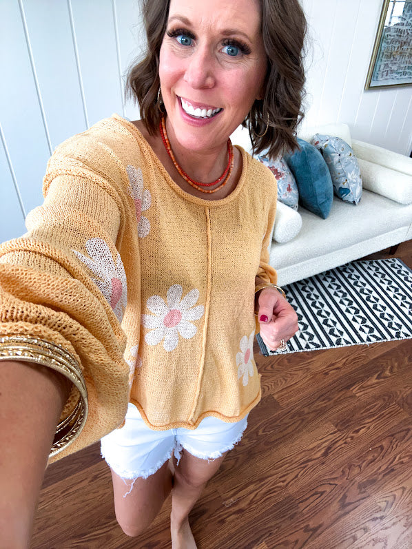 Soft, lightweight, nearly sheer knit pullover  with long sleeves, exposed seams at the shoulders and down the center with large daisy florals throughout. Available in multiple colors.
