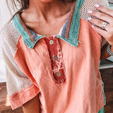 Salmon colored 3/4 sleeve blouse with striped blue and brown yarn collar, three wooden buttons on front, relaxed fit and mesh at the shoulders and sleeves.