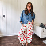 Soft, stretchy cream elastic drawstring waist pants with large red polka dots throughout, pockets and button cuffs for a balloon-like silhouette.