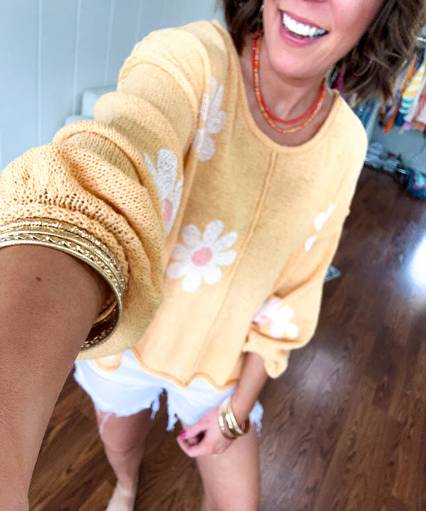 Soft, lightweight, nearly sheer knit pullover  with long sleeves, exposed seams at the shoulders and down the center with large daisy florals throughout. Available in multiple colors.