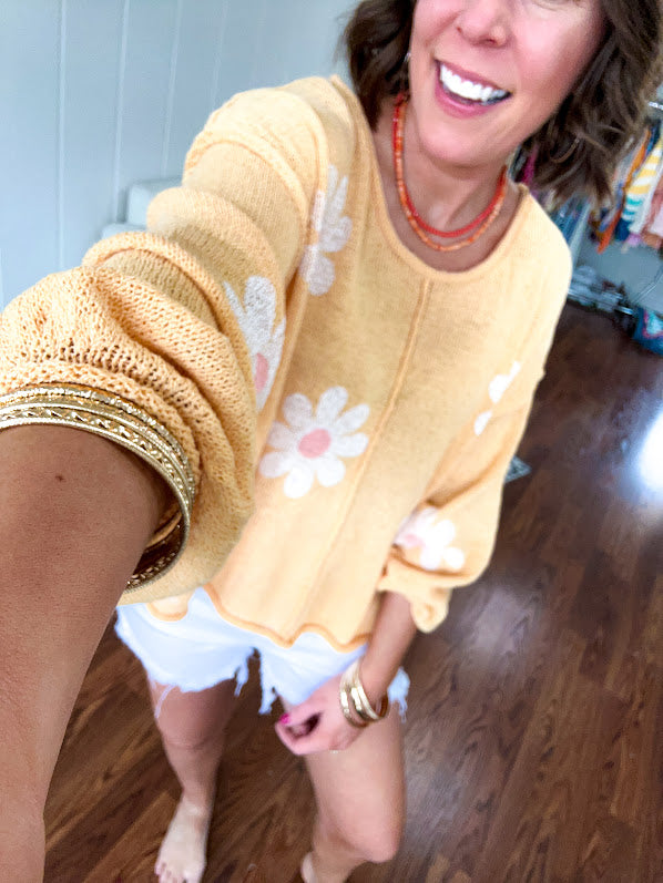 Soft, lightweight, nearly sheer knit pullover  with long sleeves, exposed seams at the shoulders and down the center with large daisy florals throughout. Available in multiple colors.