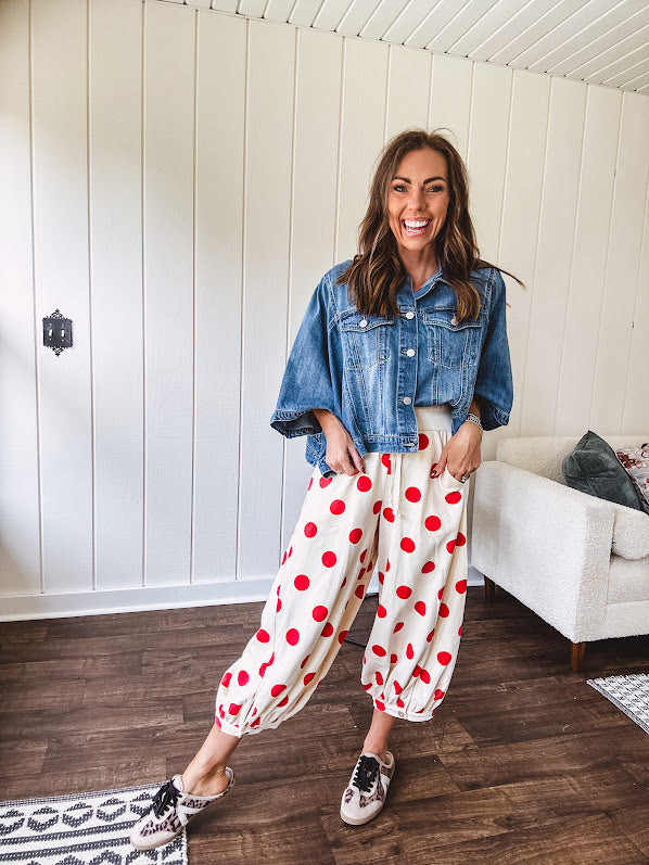 Soft, stretchy cream elastic drawstring waist pants with large red polka dots throughout, pockets and button cuffs for a balloon-like silhouette.