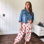 Soft, stretchy cream elastic drawstring waist pants with large red polka dots throughout, pockets and button cuffs for a balloon-like silhouette.