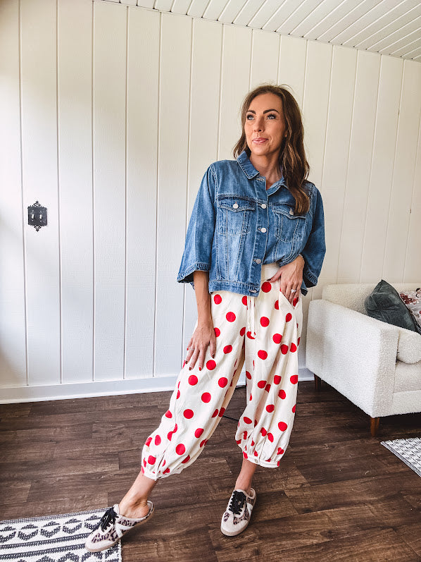 Soft, stretchy cream elastic drawstring waist pants with large red polka dots throughout, pockets and button cuffs for a balloon-like silhouette.