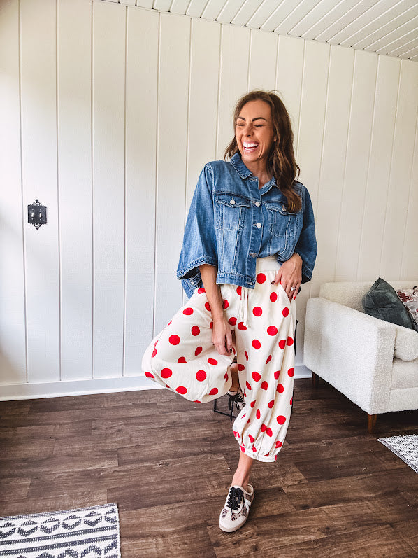 Soft, stretchy cream elastic drawstring waist pants with large red polka dots throughout, pockets and button cuffs for a balloon-like silhouette.