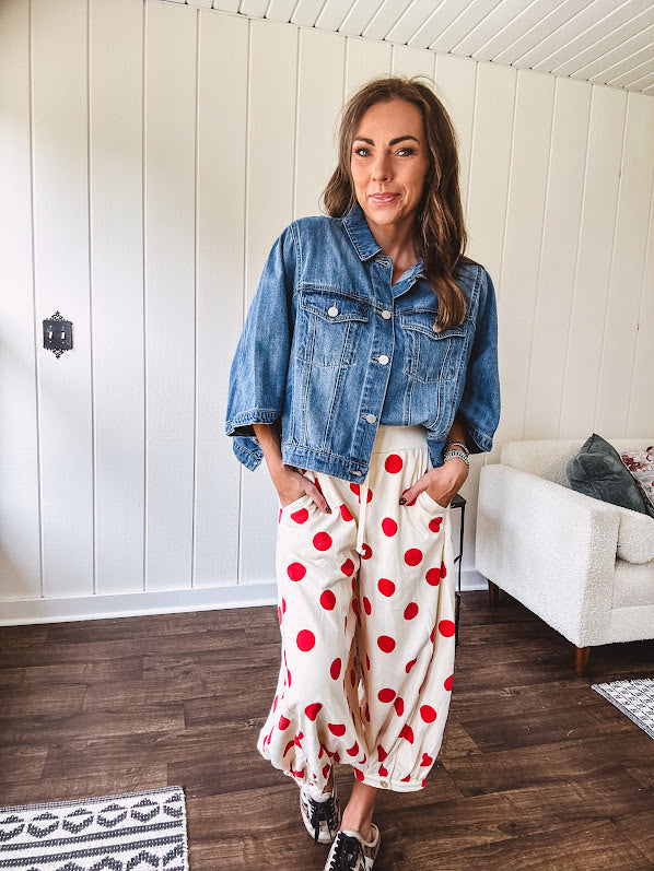 Soft, stretchy cream elastic drawstring waist pants with large red polka dots throughout, pockets and button cuffs for a balloon-like silhouette.