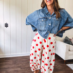Soft, stretchy cream elastic drawstring waist pants with large red polka dots throughout, pockets and button cuffs for a balloon-like silhouette.