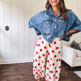 Soft, stretchy cream elastic drawstring waist pants with large red polka dots throughout, pockets and button cuffs for a balloon-like silhouette.