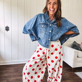 Soft, stretchy cream elastic drawstring waist pants with large red polka dots throughout, pockets and button cuffs for a balloon-like silhouette.